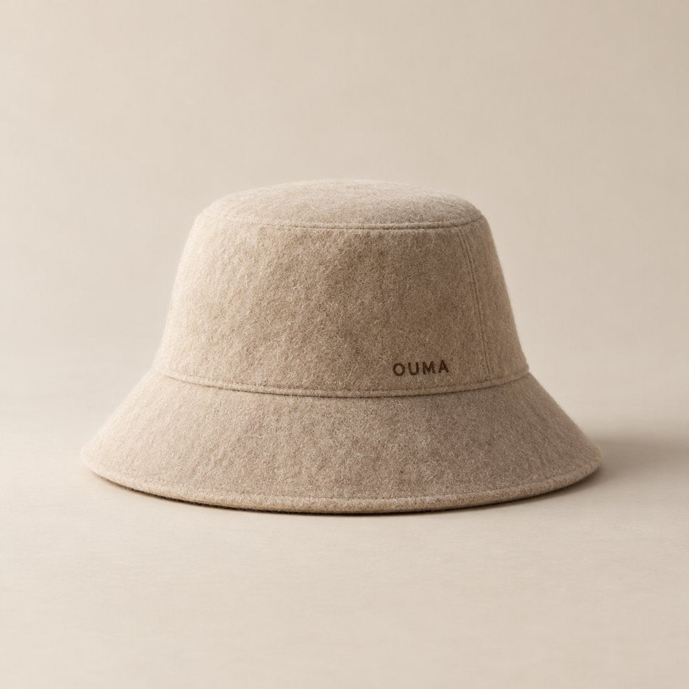 Beige bucket-style OUMA sauna hat with discreet branding — AI-generated illustration.